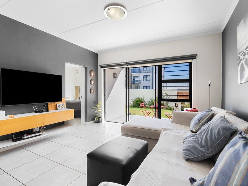 Bright living room featuring tiled flooring and large sliding glass doors providing direct access to the outdoor patio area.