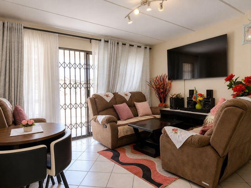 A well-maintained living room featuring tiled flooring, track lighting, and a sliding glass door with an integrated security gate for added safety.