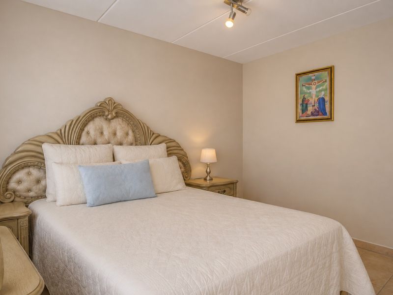 A well-maintained bedroom featuring neutral wall tones, tiled flooring, and a modern ceiling-mounted spotlight fixture.