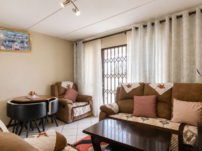 A comfortable living room featuring tiled flooring, track lighting, and a secure metal gate leading to an outdoor area.
