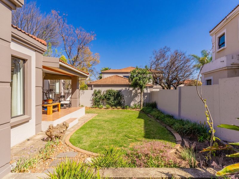A well-maintained rear garden featuring a covered patio, paved walkway, and established boundary walls, offering a private outdoor living space.