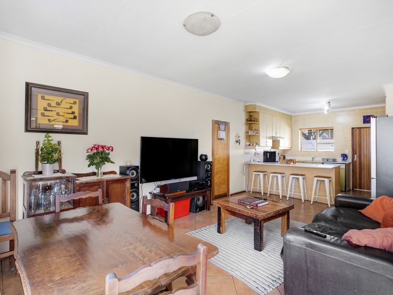 Open-plan living and dining area featuring a functional kitchen with a breakfast bar, tiled flooring, and neutral wall finishes.