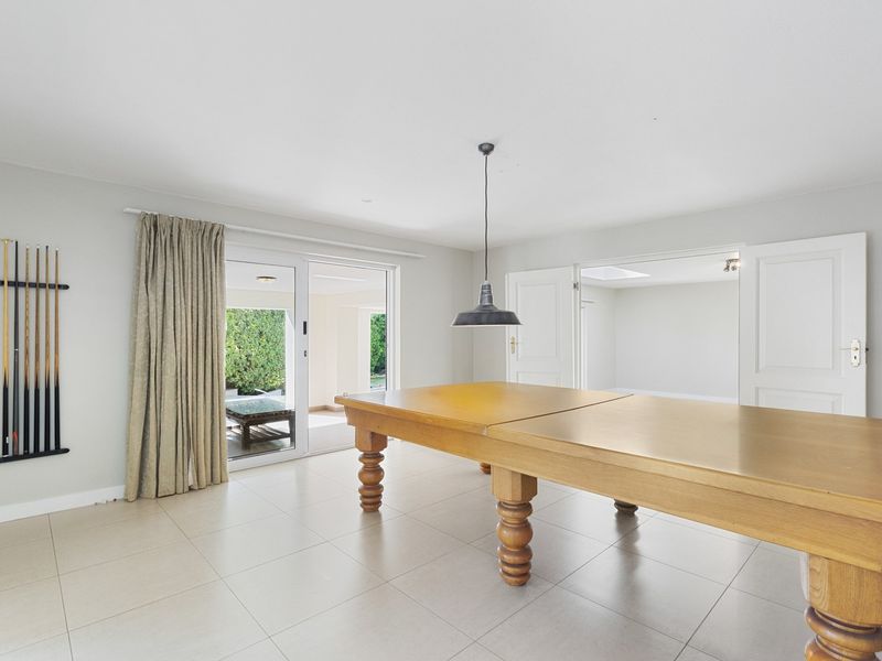 Spacious living area featuring neutral tiled flooring, a central pendant light, and sliding glass doors providing access to the outdoor patio area.