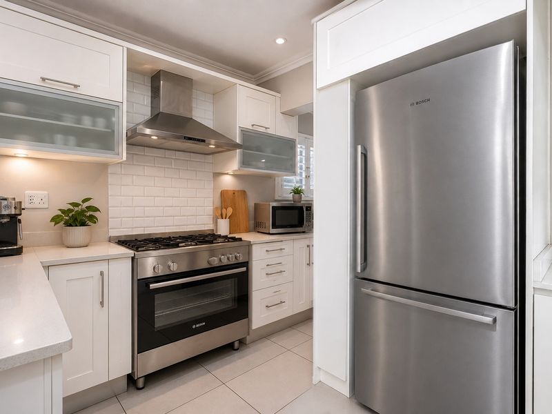 Modern kitchen featuring white shaker cabinetry, quartz countertops, subway tile backsplash, and high-quality stainless steel appliances including a gas stove and oven.