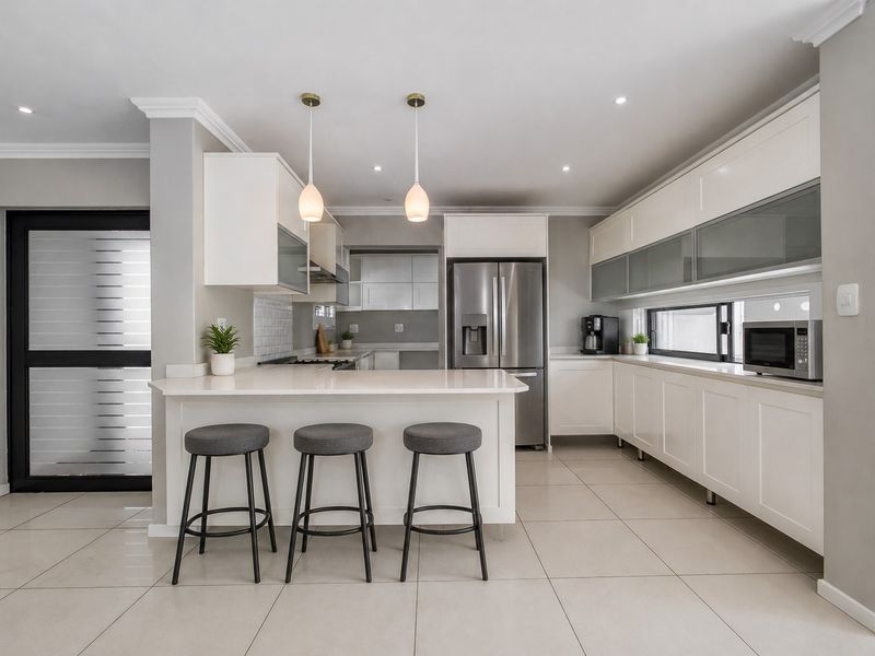 Modern, well-appointed kitchen featuring white cabinetry, quartz countertops, a breakfast bar, and high-quality finishes throughout.