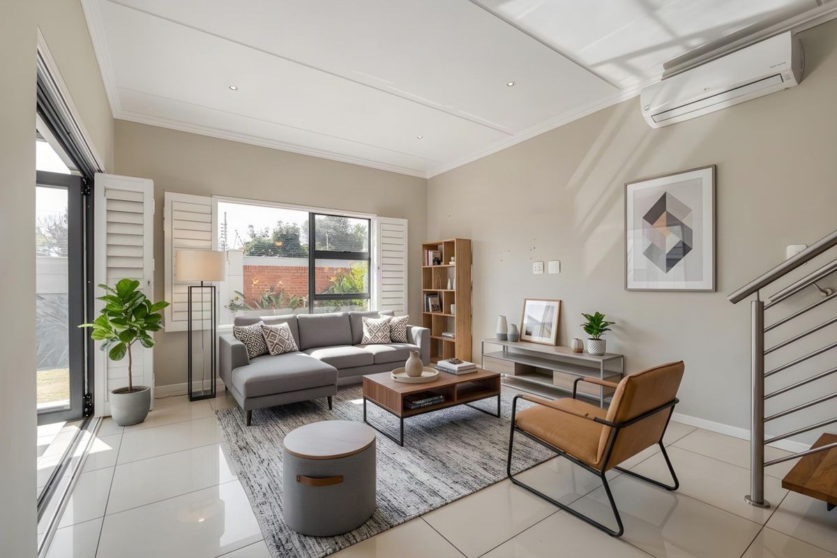 A bright and modern living room featuring tiled floors, plantation shutters, a split-system air conditioner, and direct access to an outdoor area.