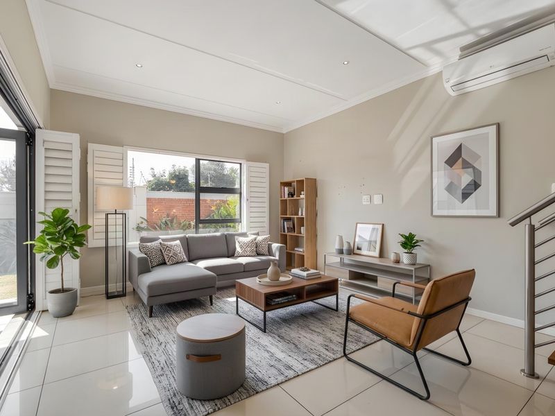 A bright and modern living room featuring tiled floors, plantation shutters, a split-system air conditioner, and direct access to an outdoor area.