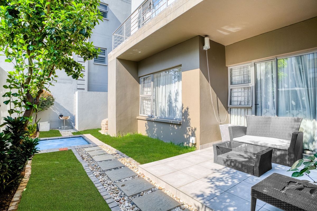 Rear exterior view featuring a tiled patio, small plunge pool, stone walkway, and artificial lawn area with access via sliding glass doors.
