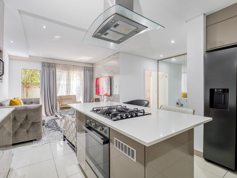 Modern open-plan kitchen and living area featuring a central island with gas cooktop, sleek cabinetry, and high-quality finishes throughout.