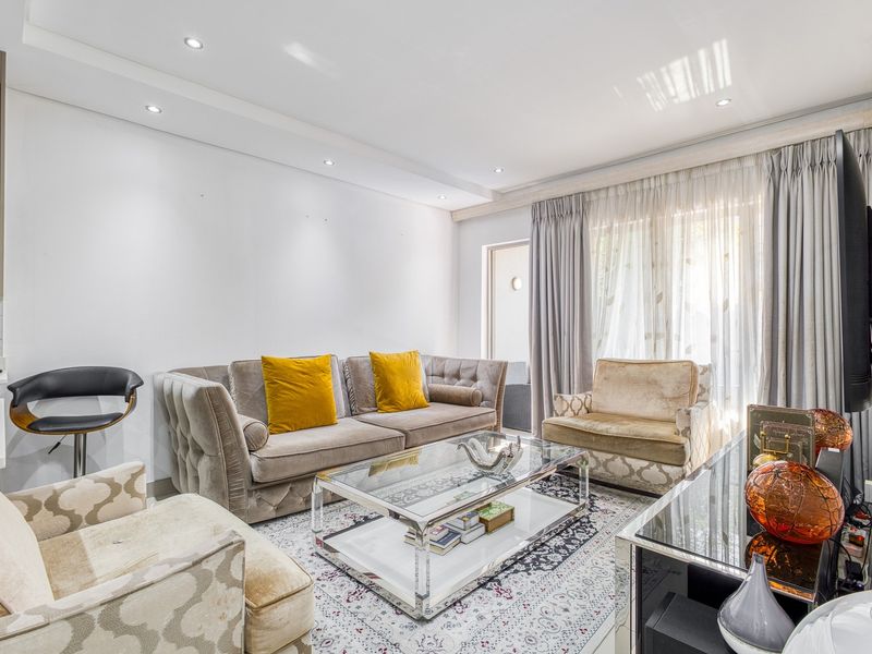 Modern open-plan living area featuring recessed ceiling lighting, integrated kitchen cabinetry with built-in microwave, and large sliding glass doors leading to an outdoor space.