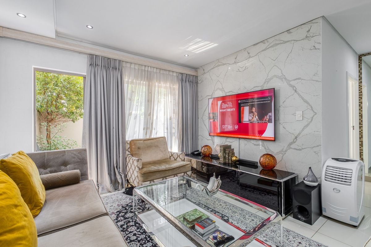 Modern living room featuring a striking marble-look feature wall, recessed downlighting, and large sliding glass doors providing natural light and garden access.