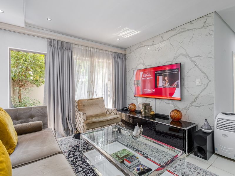 Modern living room featuring a striking marble-look feature wall, recessed downlighting, and large sliding glass doors providing natural light and garden access.