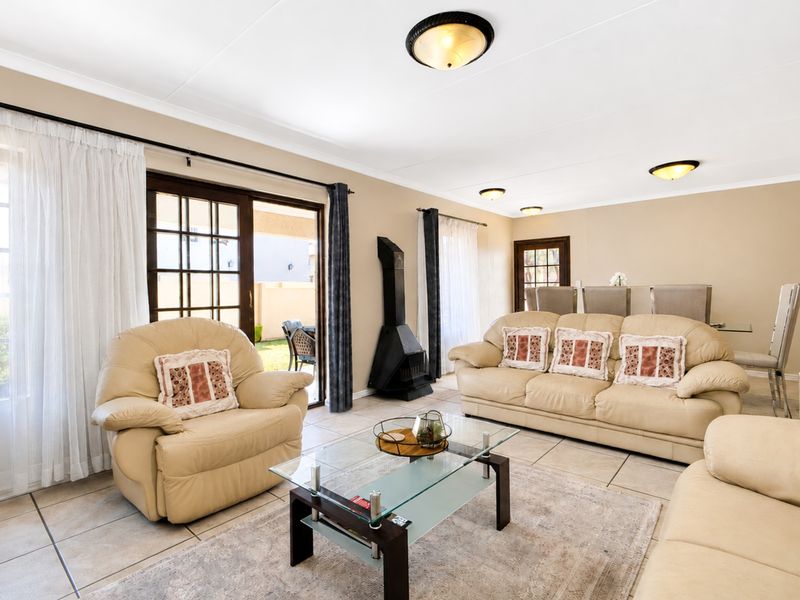 Spacious living room featuring tiled floors, a freestanding fireplace, and sliding glass doors providing direct access to the outdoor patio area.
