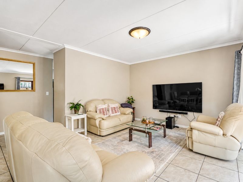 A comfortable living room featuring neutral wall tones, tiled flooring, and a large sliding glass door providing access to the outdoor area.