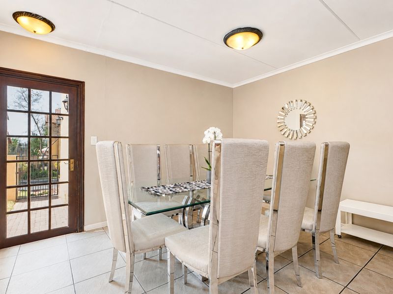 A dining room featuring tiled flooring, flush mount ceiling lights, and a glass paneled door providing access to the exterior.