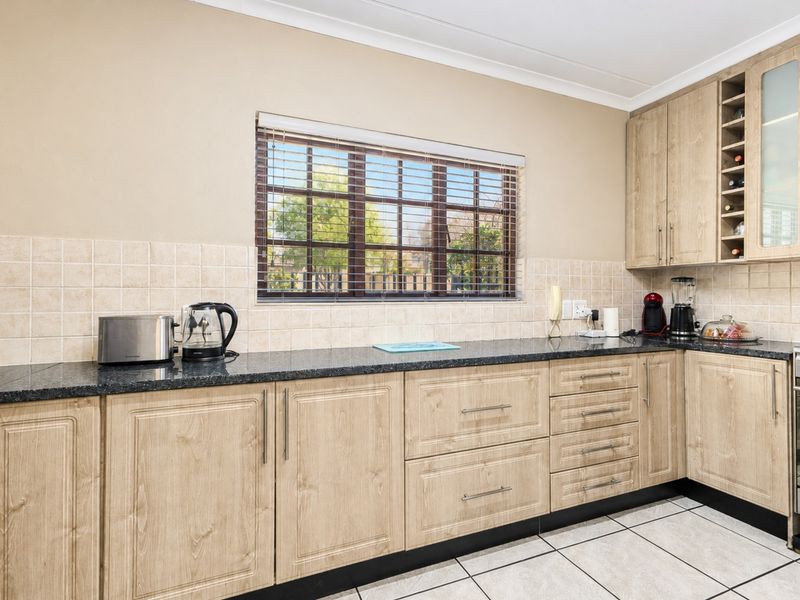 A functional kitchen featuring light wood-finish cabinetry, granite countertops, ceramic tile backsplash, and tiled flooring, offering ample storage and workspace.