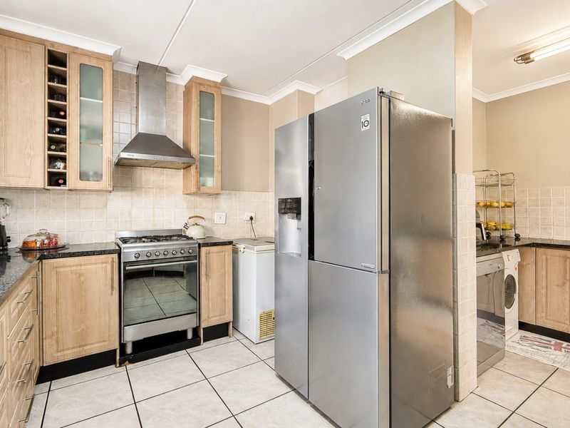 Functional kitchen featuring light wood cabinetry, granite countertops, tiled backsplash, and a stainless steel gas stove with extractor fan.