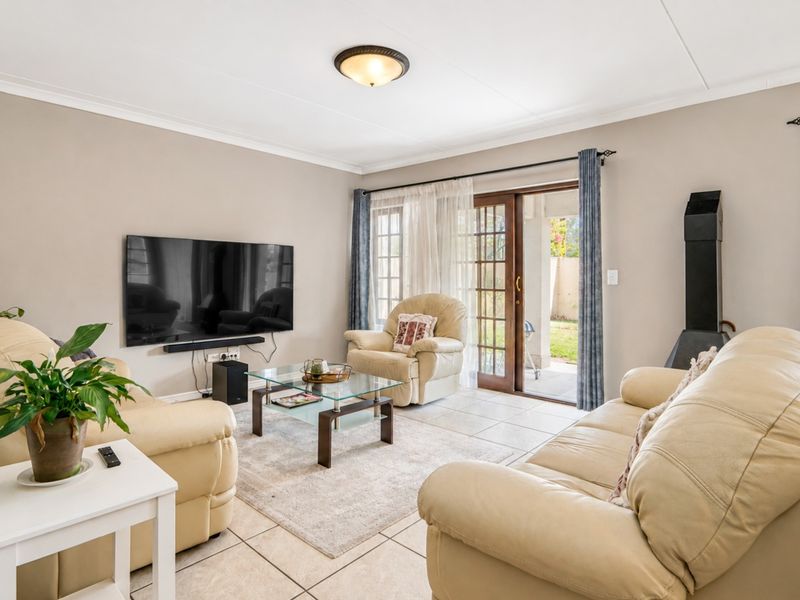 A comfortable living room featuring tiled flooring, a freestanding fireplace, and a sliding glass door providing direct access to the outdoor patio area.