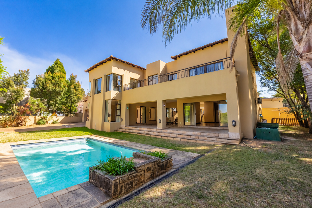 Rear view of a two-story house featuring a swimming pool, tiled patio, upper-level balcony, and large sliding glass doors opening to the interior.