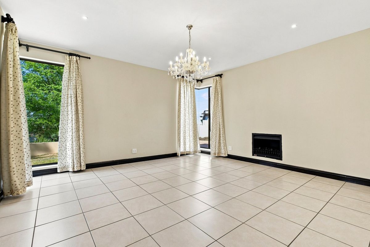 Spacious living room featuring neutral tiled flooring, a built-in fireplace, and a decorative chandelier, offering a bright and versatile space.