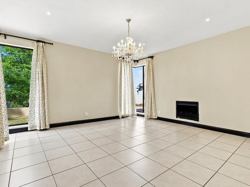 Spacious living room featuring neutral tiled flooring, a built-in fireplace, and a decorative chandelier, offering a bright and versatile space.
