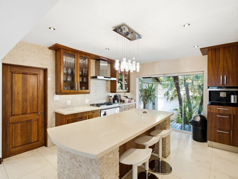 Modern kitchen featuring a central island with stone countertops, built-in appliances, mosaic tile backsplash, and direct access to an outdoor patio area.
