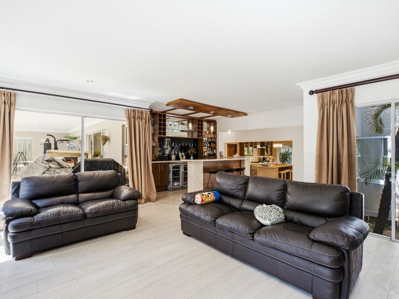 Spacious open-plan living area featuring a built-in bar with integrated wine storage, light laminate flooring, and large sliding doors providing access to the outdoors.