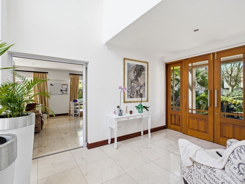 Bright and spacious entrance hall featuring double wooden doors, polished tiled flooring, and high ceilings, providing a welcoming transition into the home.