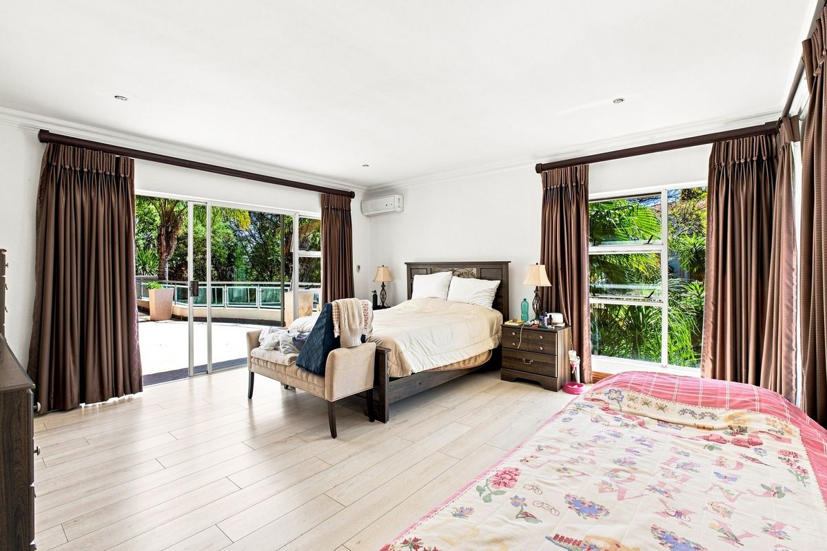 Spacious bedroom featuring light laminate flooring, recessed lighting, an air conditioning unit, and large sliding glass doors providing access to an outdoor patio area.