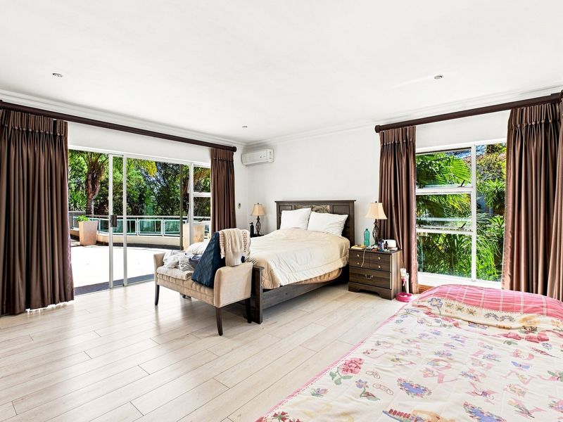 Spacious bedroom featuring light laminate flooring, recessed lighting, an air conditioning unit, and large sliding glass doors providing access to an outdoor patio area.