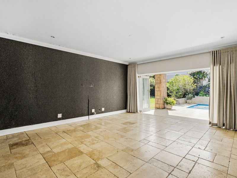 Spacious living area featuring travertine flooring, a textured feature wall, and large stacking doors opening onto a patio and pool area.