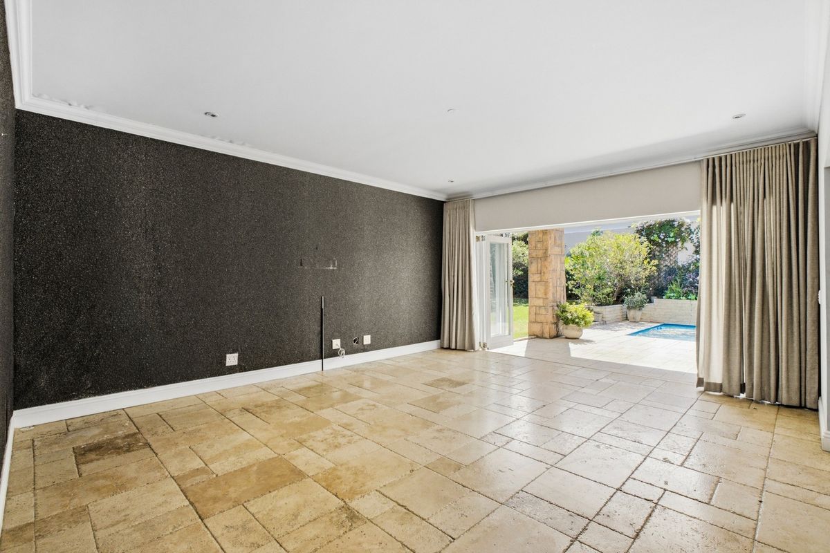 Spacious living area featuring travertine flooring, a textured feature wall, and large stacking doors opening onto a patio and pool area.