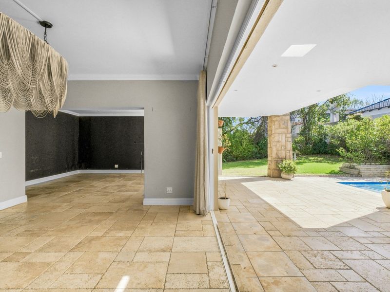 Spacious open-plan living area featuring stone tile flooring and seamless indoor-outdoor flow through large stacking glass doors leading to the patio and pool.