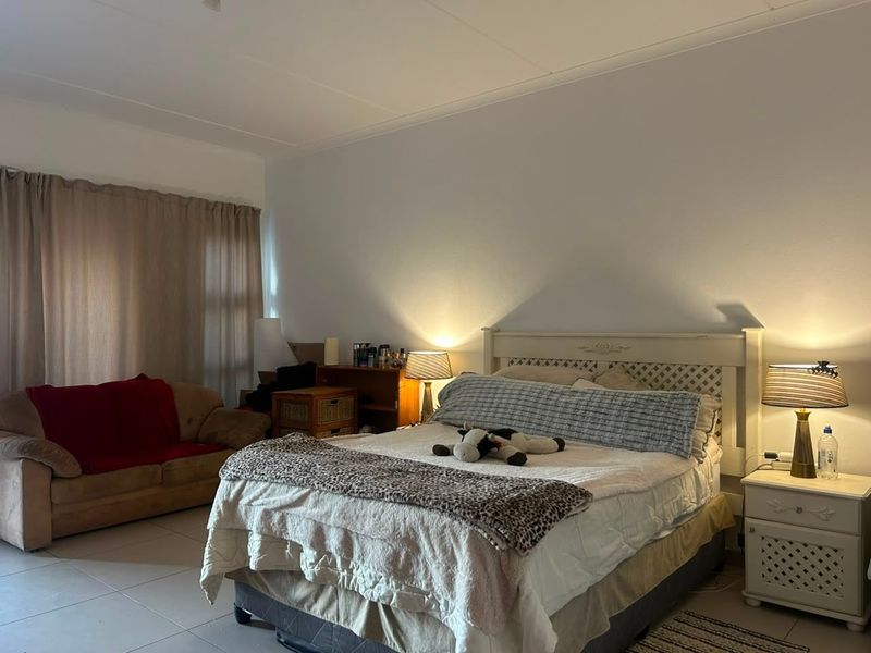 A spacious bedroom featuring tiled flooring and neutral wall finishes, offering a comfortable layout with natural light through the window.