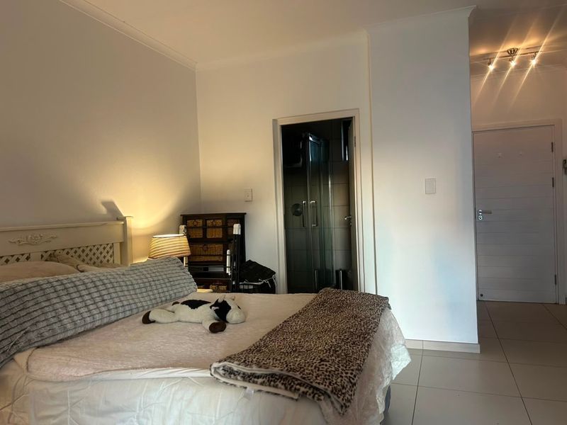 A well-maintained bedroom featuring tiled flooring, recessed ceiling lighting, and direct access to an en-suite bathroom.