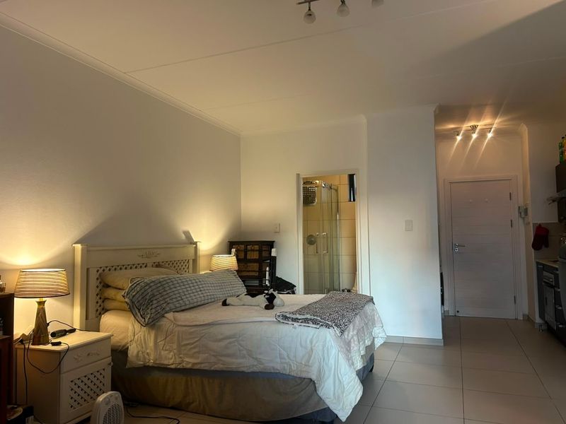 A bedroom featuring tiled flooring, recessed lighting, and an attached en-suite bathroom with a glass shower enclosure.