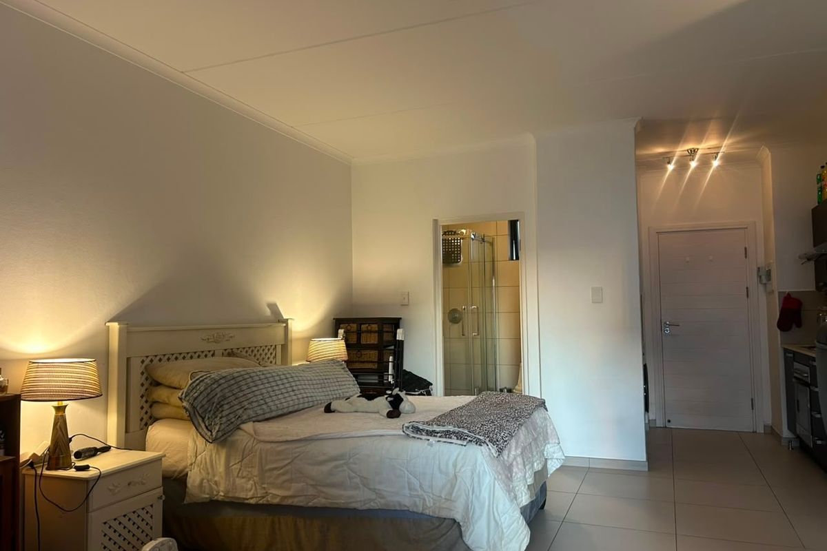 A bedroom featuring tiled flooring, recessed lighting, and an attached en-suite bathroom with a glass shower enclosure.