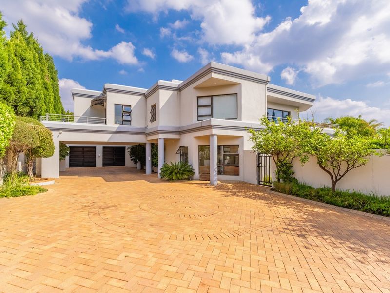 A modern double-story residential property featuring a spacious paved driveway, double garage, and upper-level balcony with clean architectural lines.