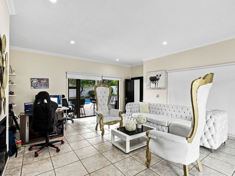 Spacious living room featuring tiled flooring, recessed lighting, and sliding glass doors providing direct access to the outdoor pool area.