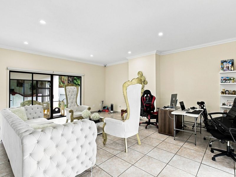 Spacious living area featuring neutral tiled flooring, recessed downlights, and large sliding glass doors providing access to the outdoor space.