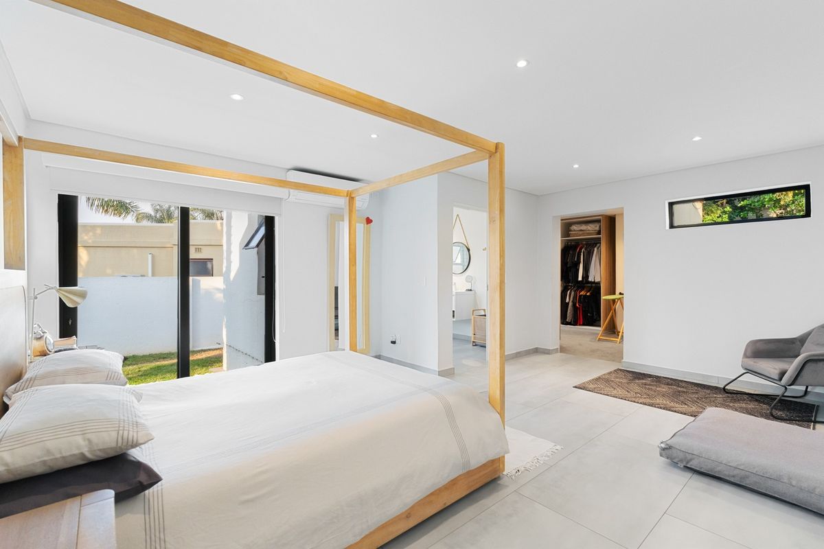 Spacious modern bedroom featuring tiled floors, recessed lighting, a split-system air conditioner, and direct access to a walk-in closet and outdoor area.
