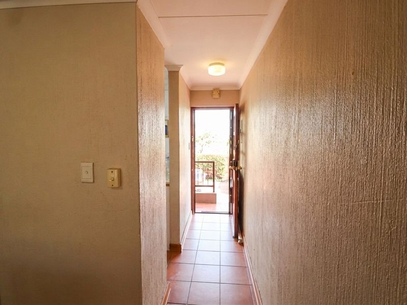 A functional hallway featuring tiled flooring and textured walls, leading directly to an external entrance.