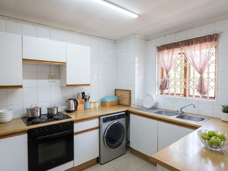 A functional kitchen featuring white cabinetry, wood-look countertops, a built-in oven and hob, and a double sink with a window view.