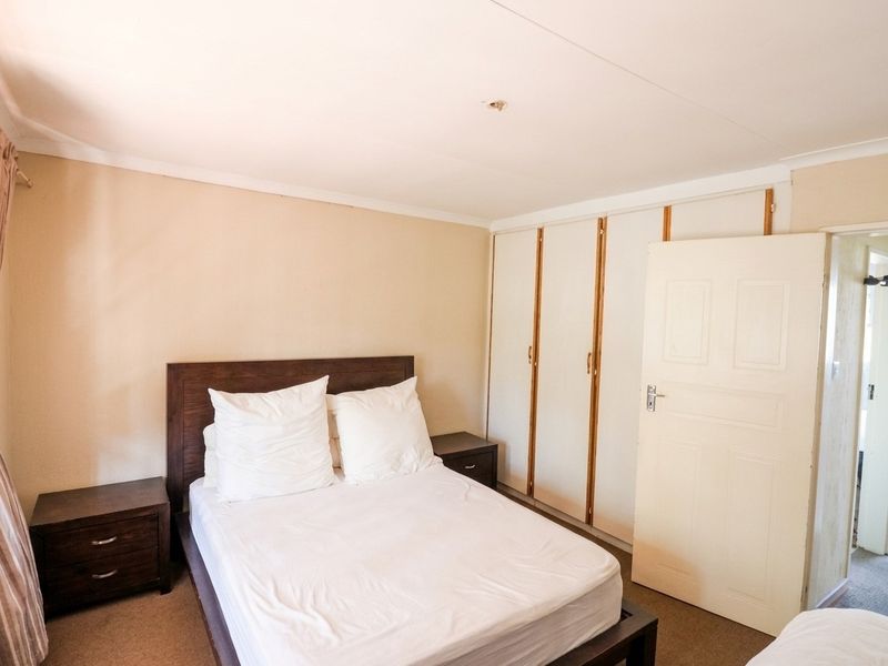 A bedroom featuring built-in cupboards and carpeted flooring, offering a functional space with potential for cosmetic updates.