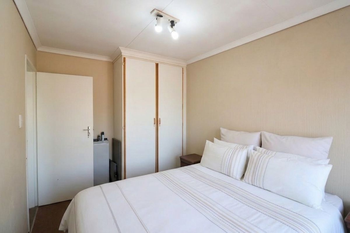 A functional bedroom featuring a built-in wardrobe, neutral wall finishes, and coving detail, providing a clean and simple living space.