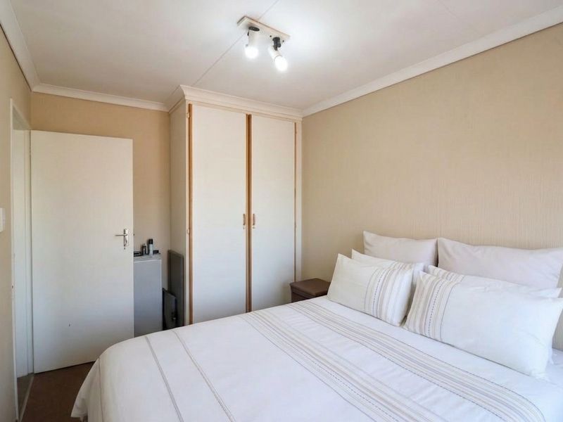 A functional bedroom featuring a built-in wardrobe, neutral wall finishes, and coving detail, providing a clean and simple living space.