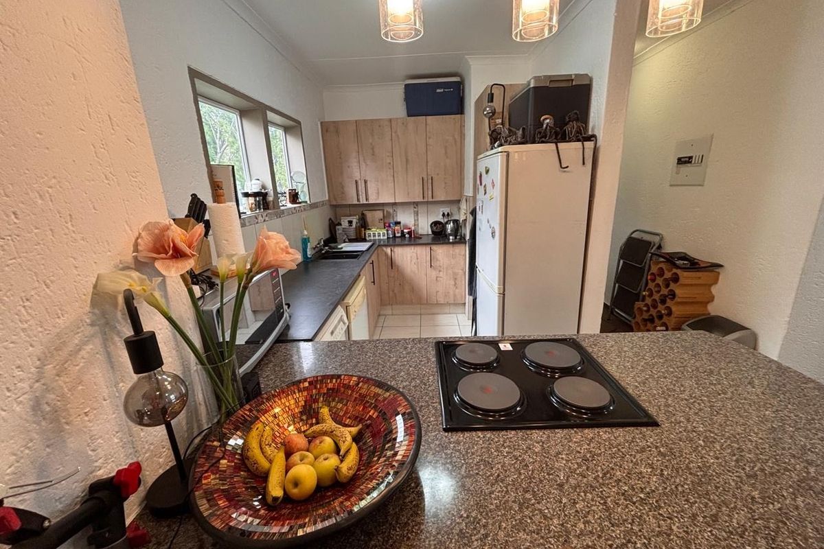 A functional kitchen featuring laminate cabinetry, granite countertops, and a built-in electric hob, offering a practical layout for daily meal preparation.