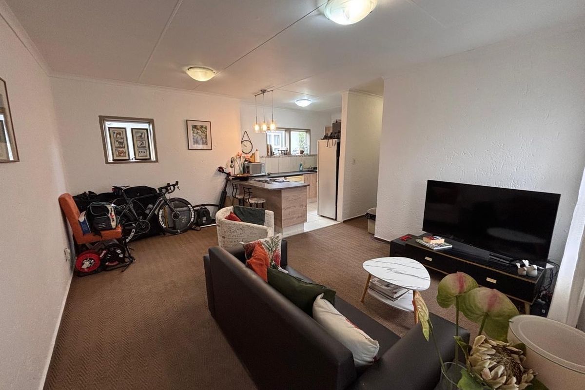 Open plan living area featuring a combined lounge and kitchen space with a breakfast bar and neutral finishes.