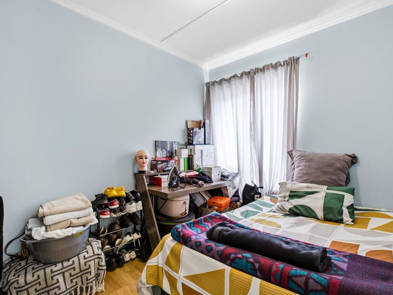 A functional bedroom featuring laminate flooring and neutral wall finishes, providing a comfortable space with natural light through the window.