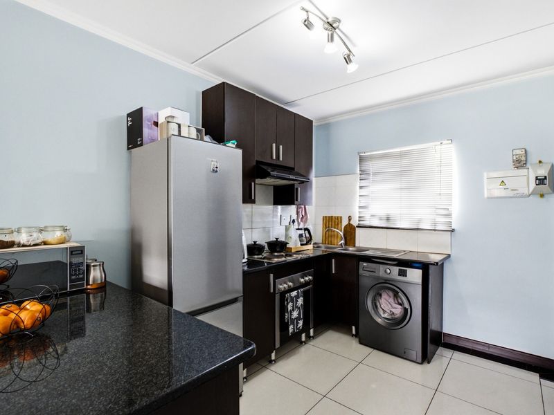 A functional kitchen featuring dark wood cabinetry, granite countertops, tiled flooring, and integrated appliance spaces, providing a clean and practical cooking area.